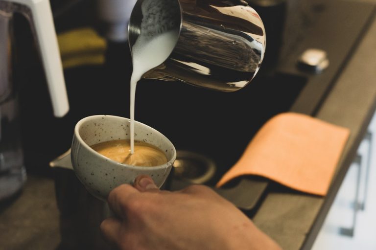 příprava kávy cappuccino nalíváním našlehaného mléka do espressa