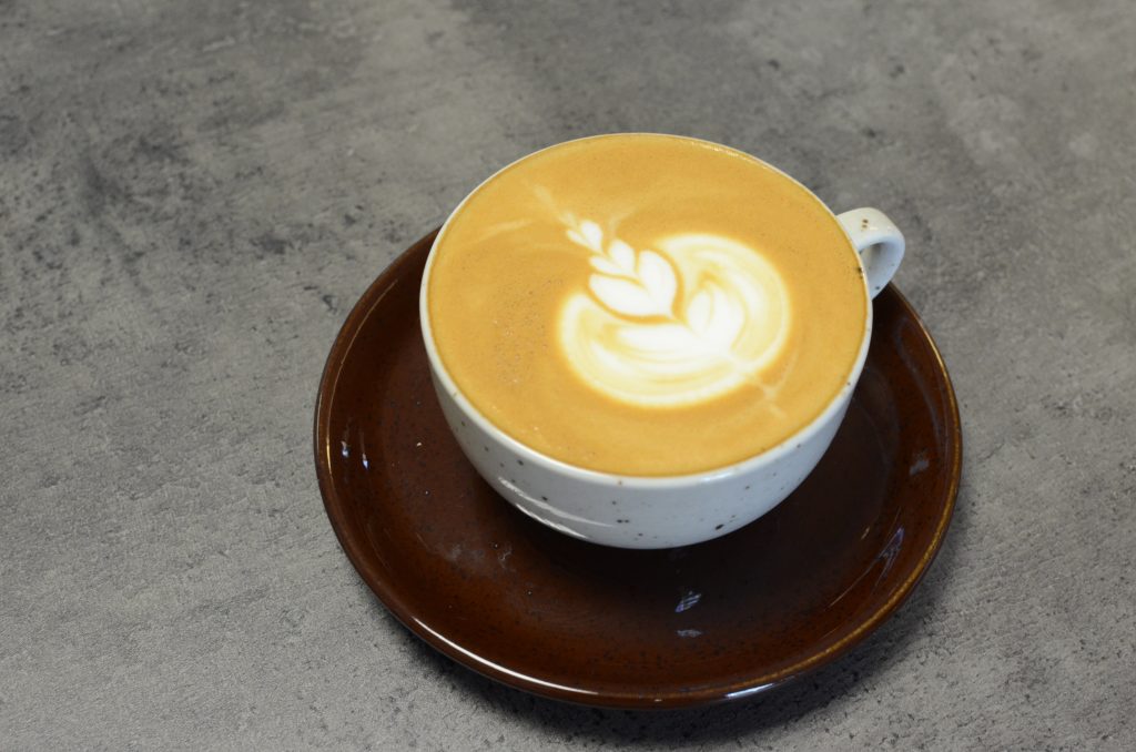 Šálek kávy Caffe Latte zdobené obrázkem technikou latte art