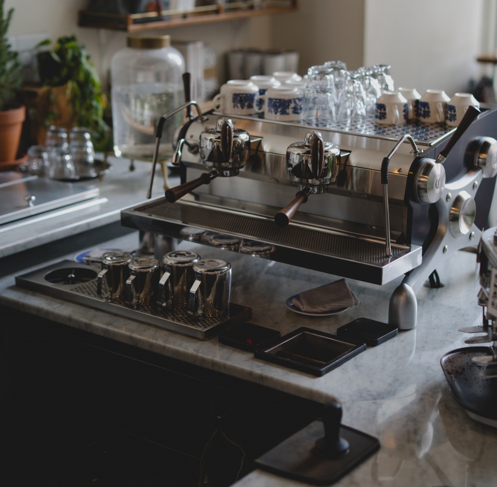 dvoupákový stříbrná kávovar na kavárenském baru se zabudovaným ostřikovačem baristických konviček