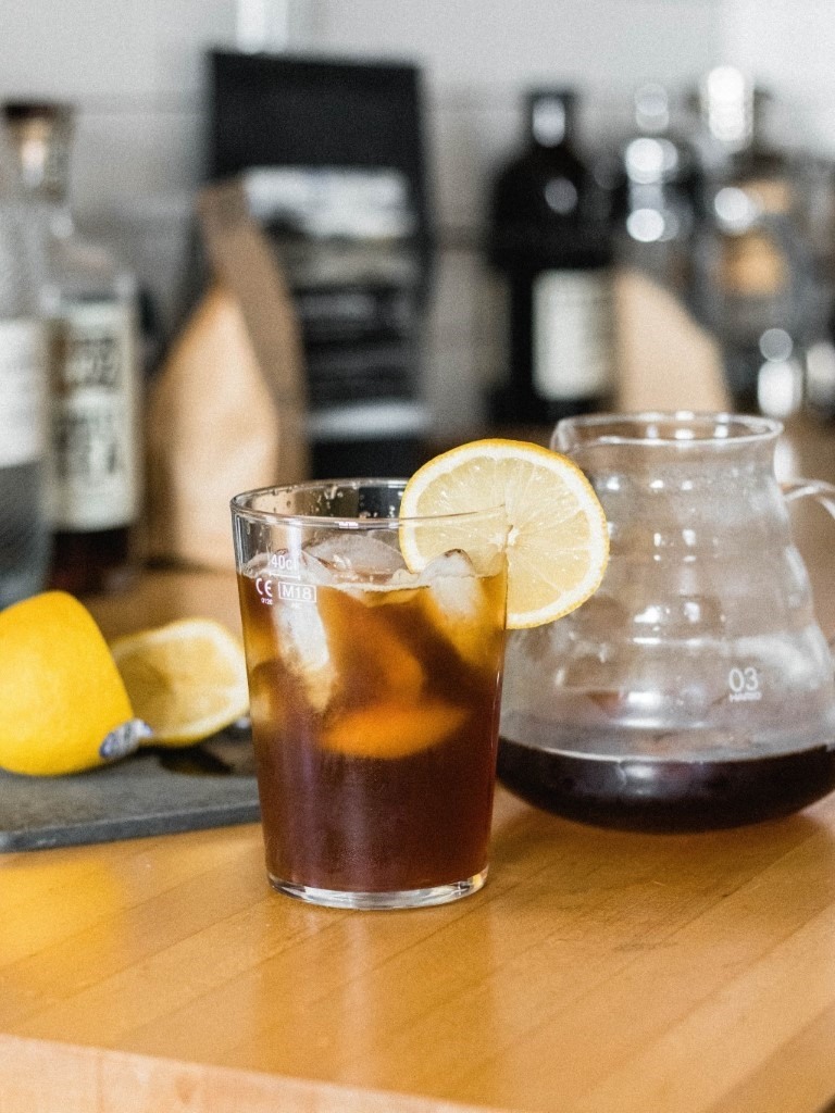 Barista připravuje kávové drinky v moderně zařízené kavárně.