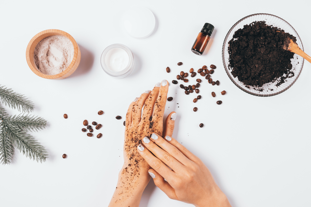 Domácí kávový peeling - ruce aplikují exfoliátor z mleté kávy na pokožku
