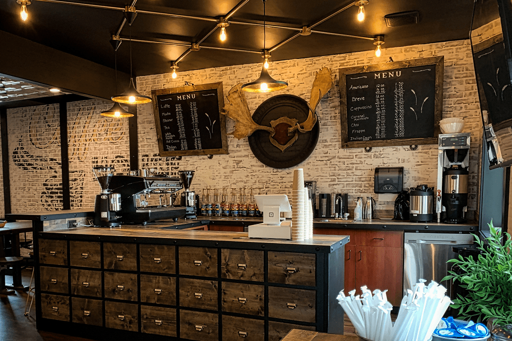 pohled na dřevěný bar v kavárně s kávovarem, kasou a kávovým příslušenstvím