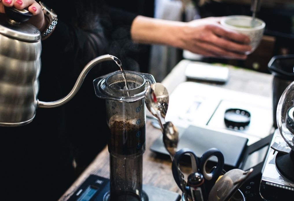 barista připravuje filtrovanou kávu v AeroPressu