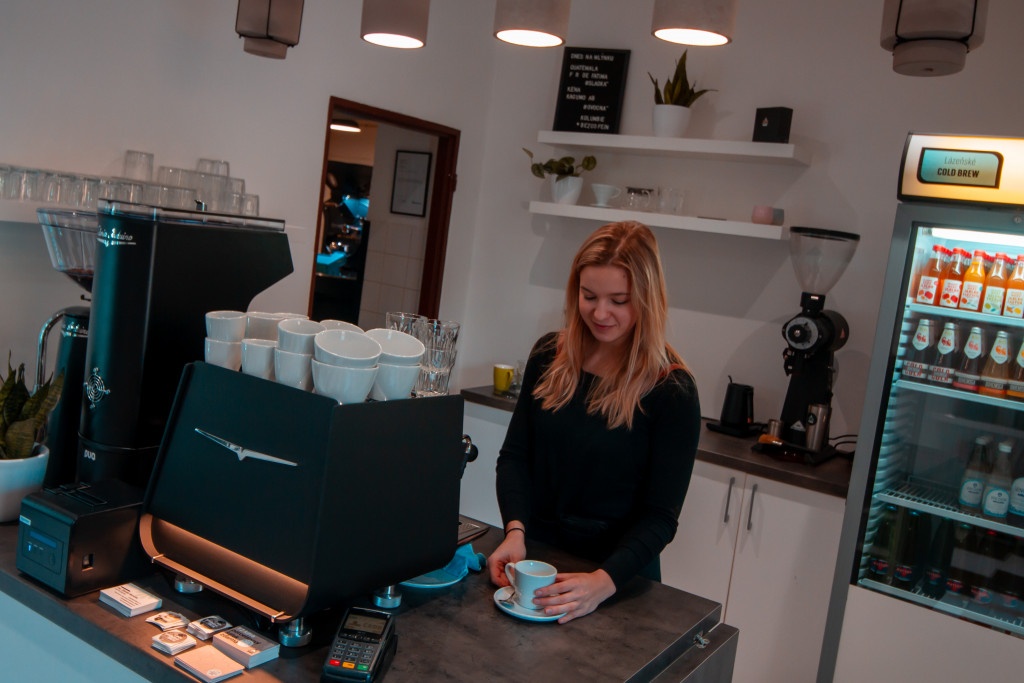 baristka podává zákazníkovi šálek s kávou