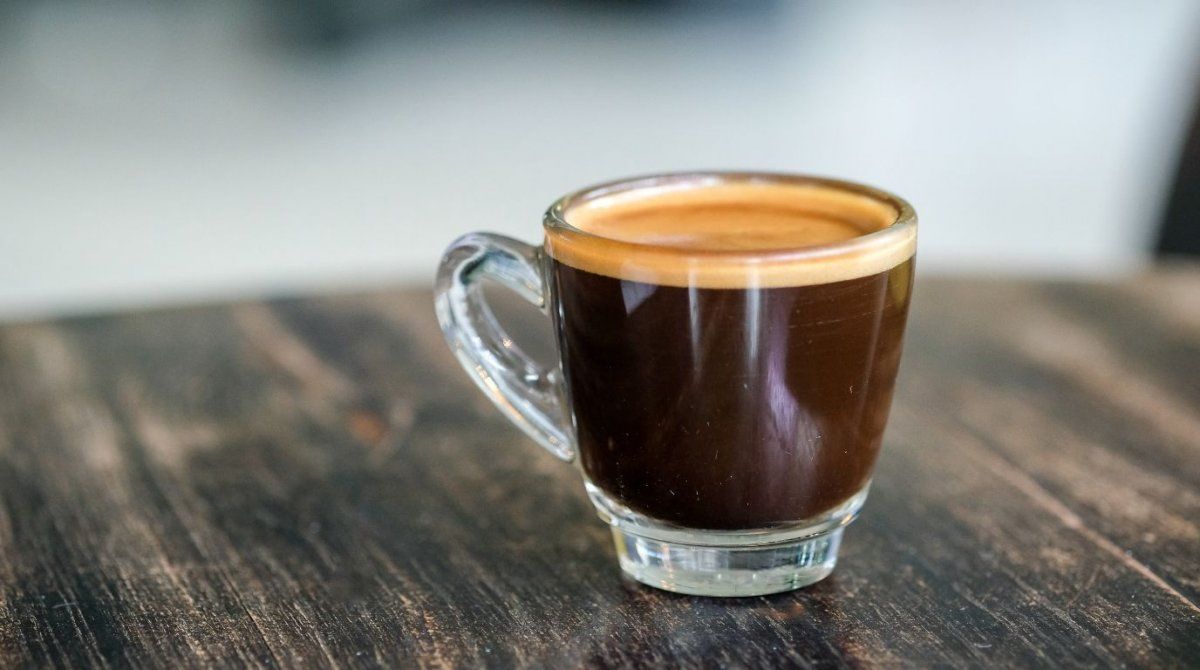 espresso-123 Skleněný hrneček espressa s cremou na tmavém dřevěném stole